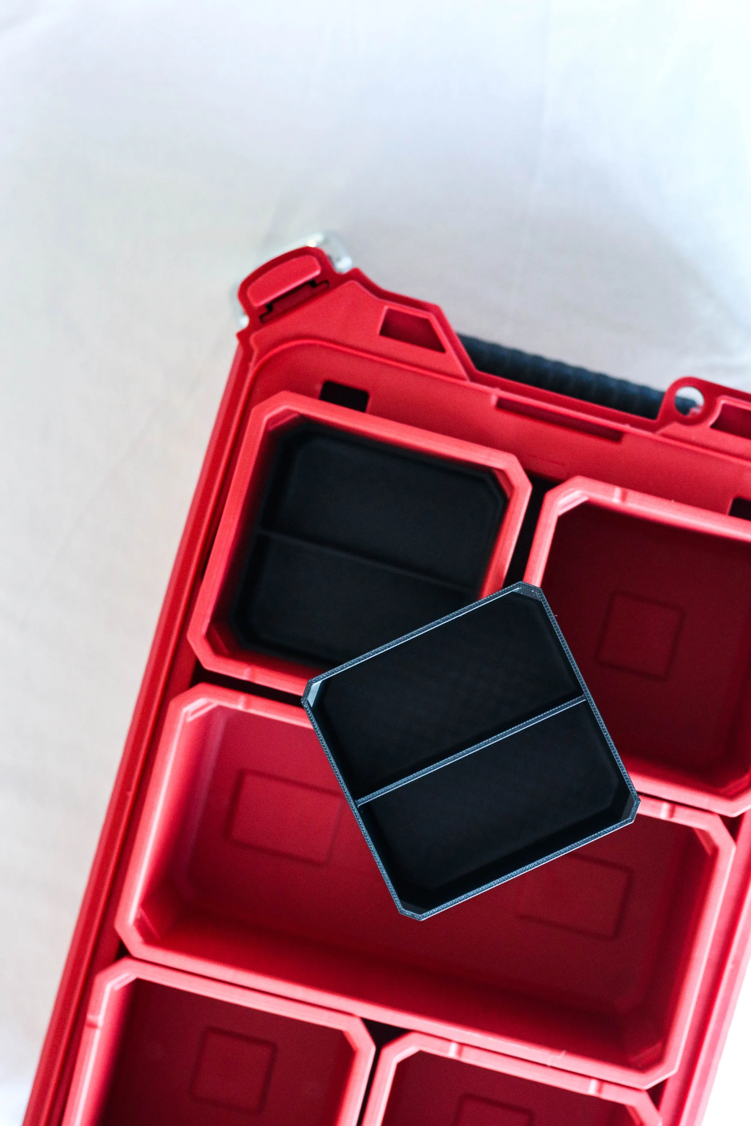 Close-up of a red plastic toolbox with black insert trays