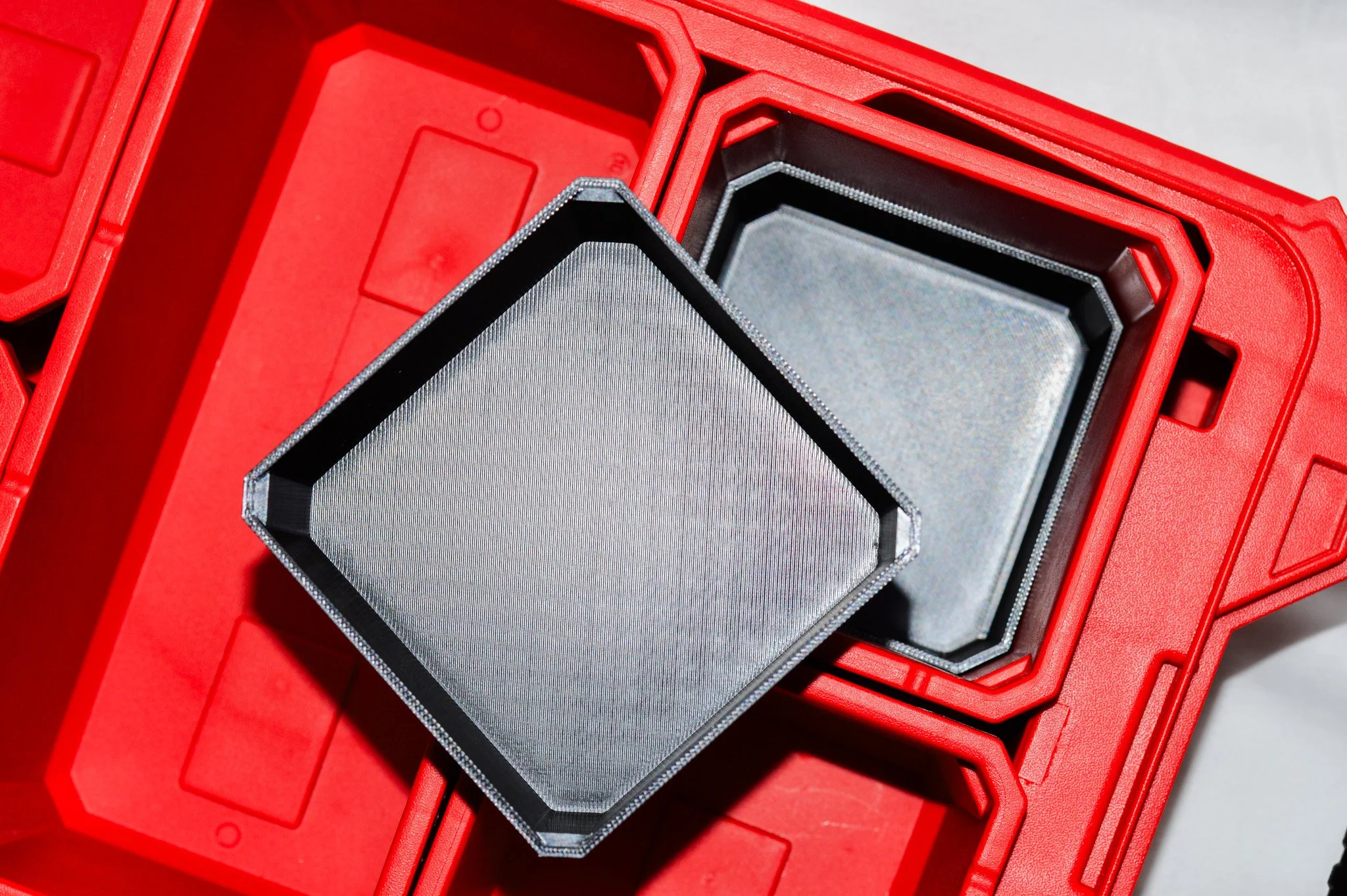 Close-up of a hexagonal metallic object placed inside a red plastic container with multiple sections.