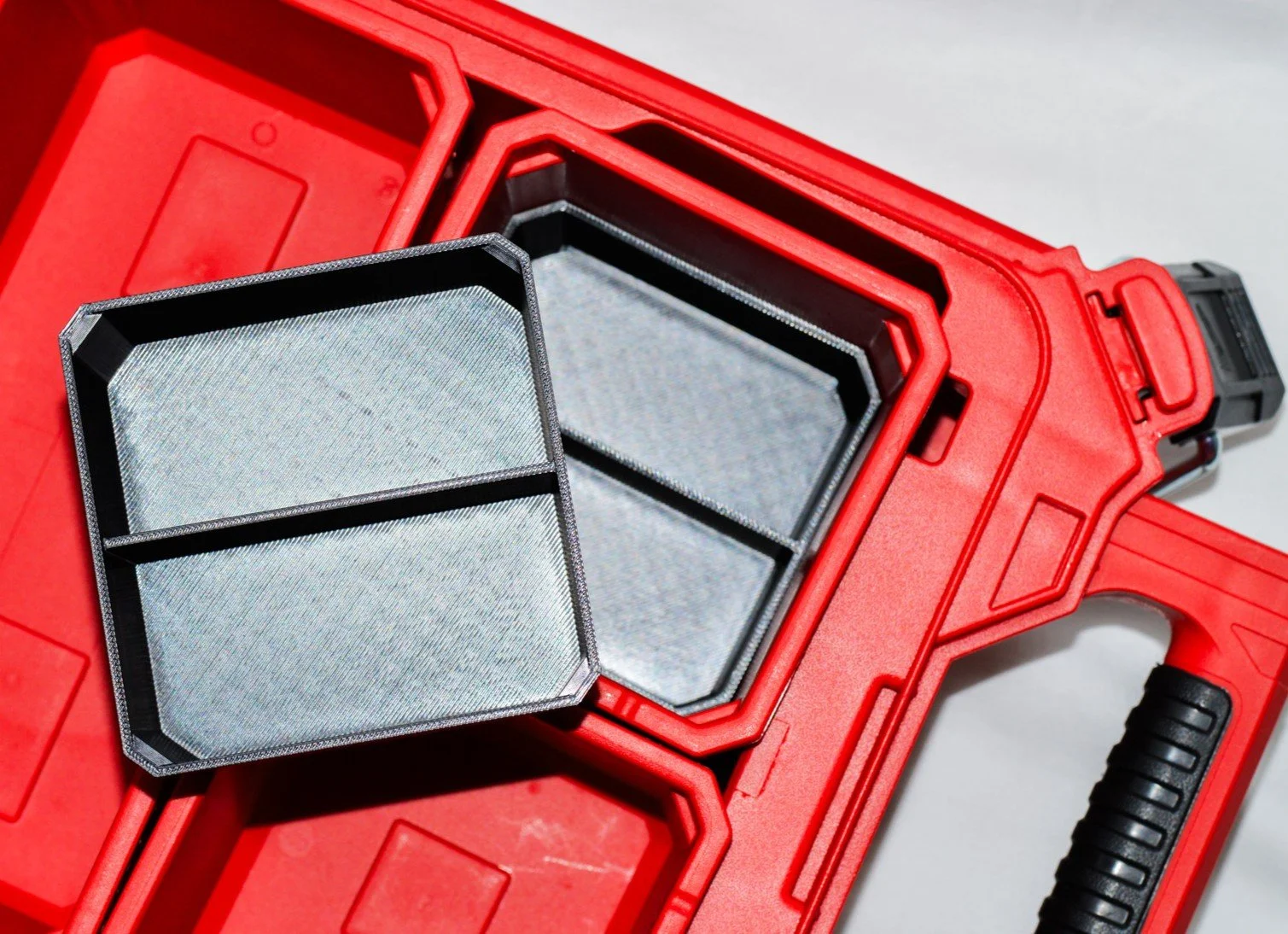 A red toolbox with an open compartment containing a magnetic filter screen that is divided into two sections.