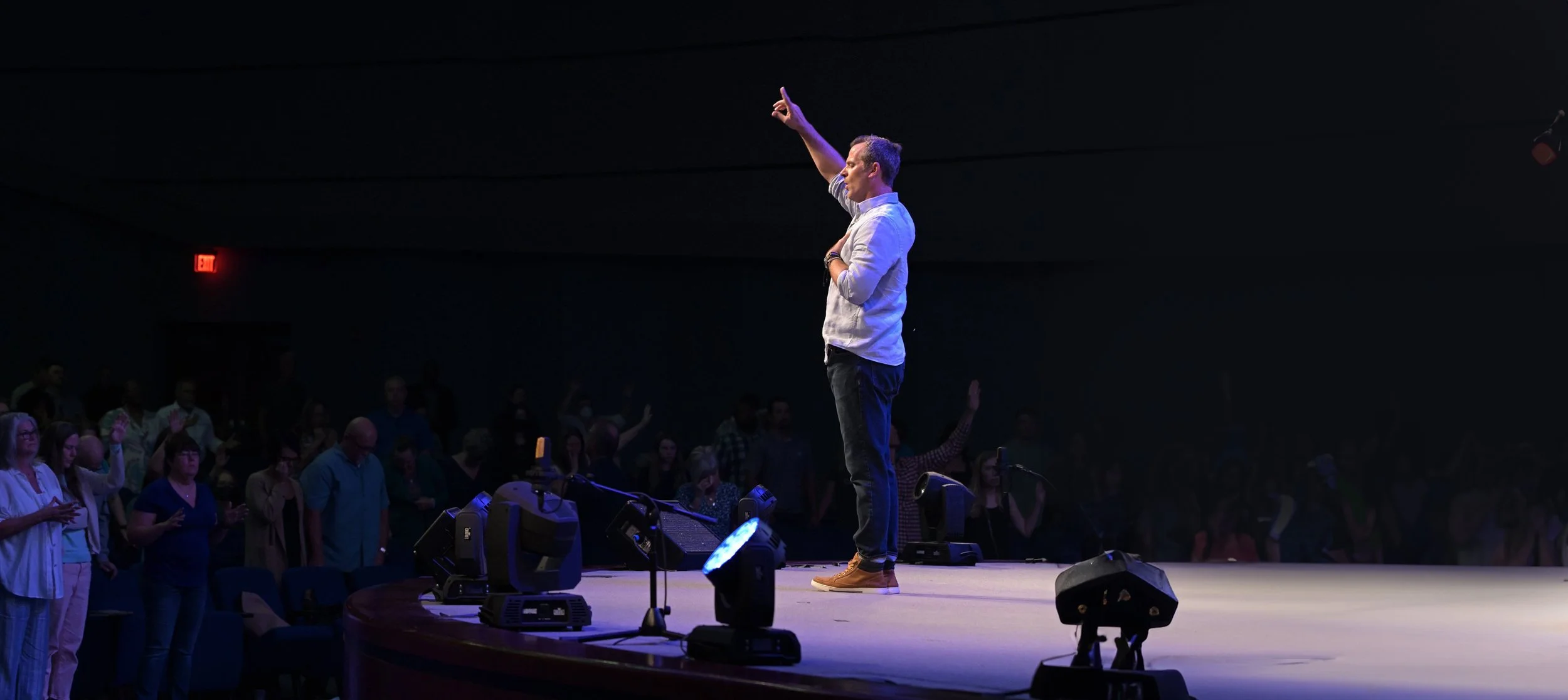 Pastor Shawn on stage at Family Worship Center praying over the congregation.