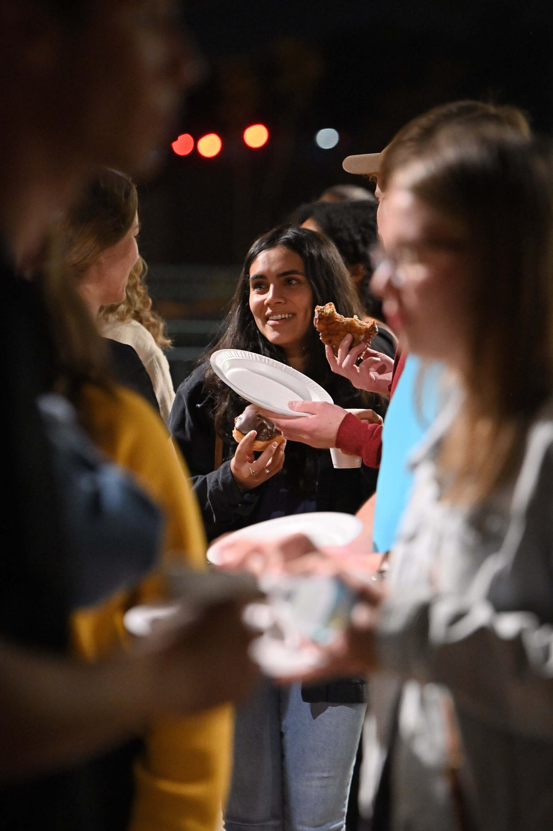 A group of young adults laughing and eating during a young adult event.