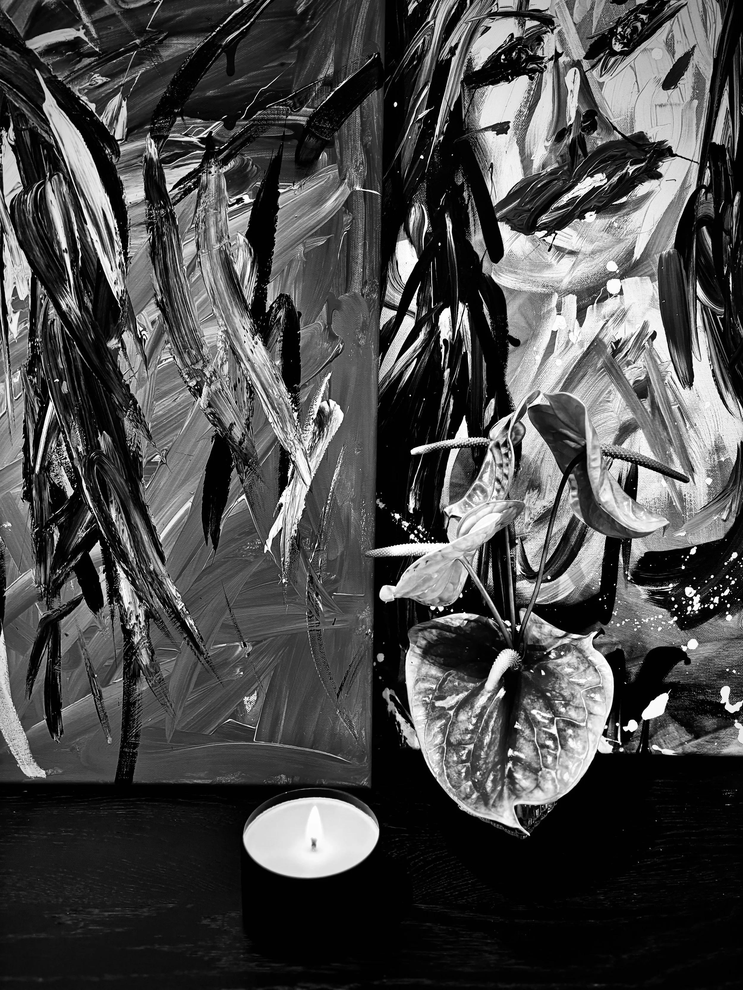 Black and white abstract painting with bold, expressive brushstrokes, depicting a plant with large leaves and a single lit candle on a table.