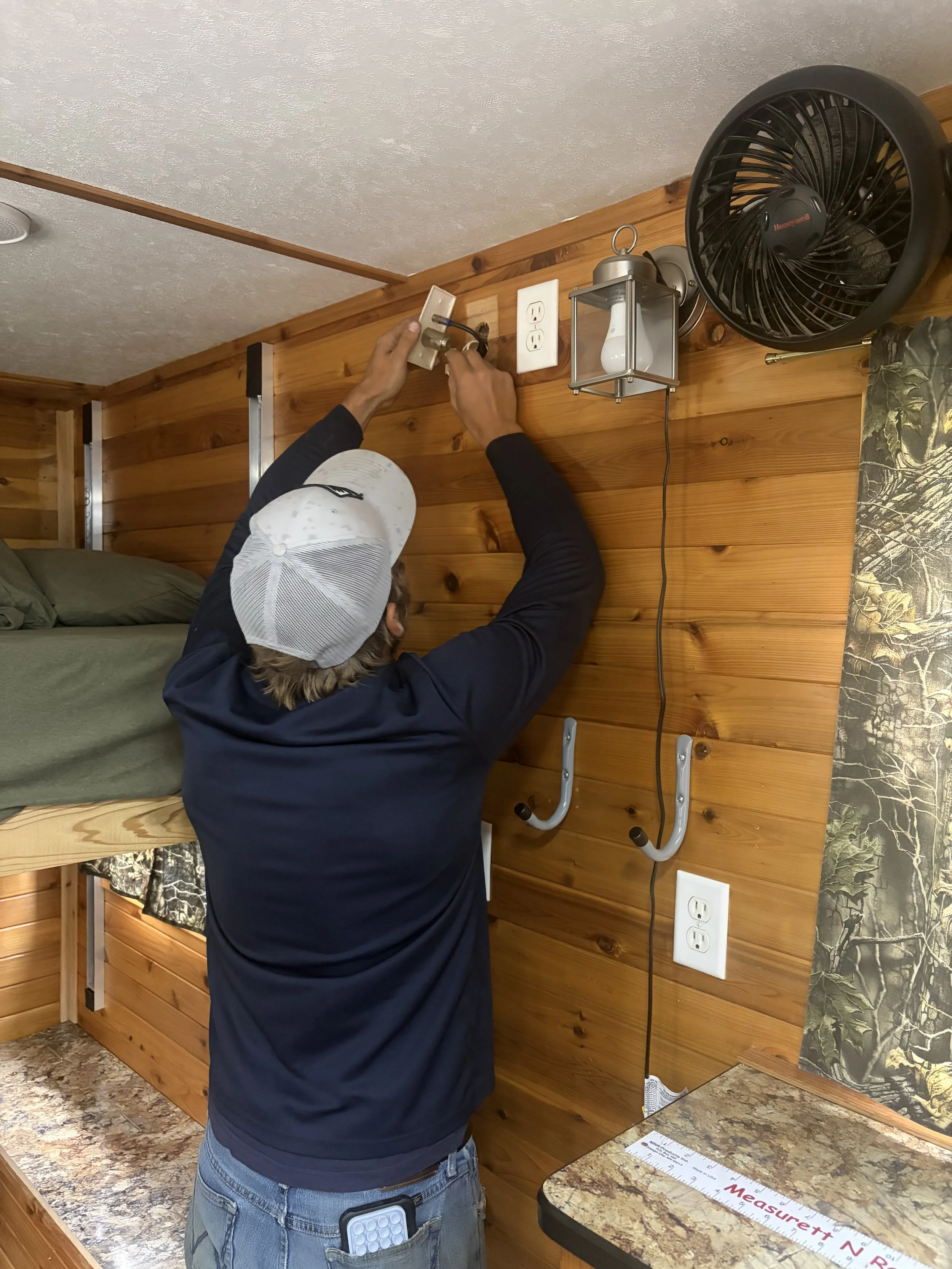 North Country Outdoors technician repairing electrical equipment in an ice house