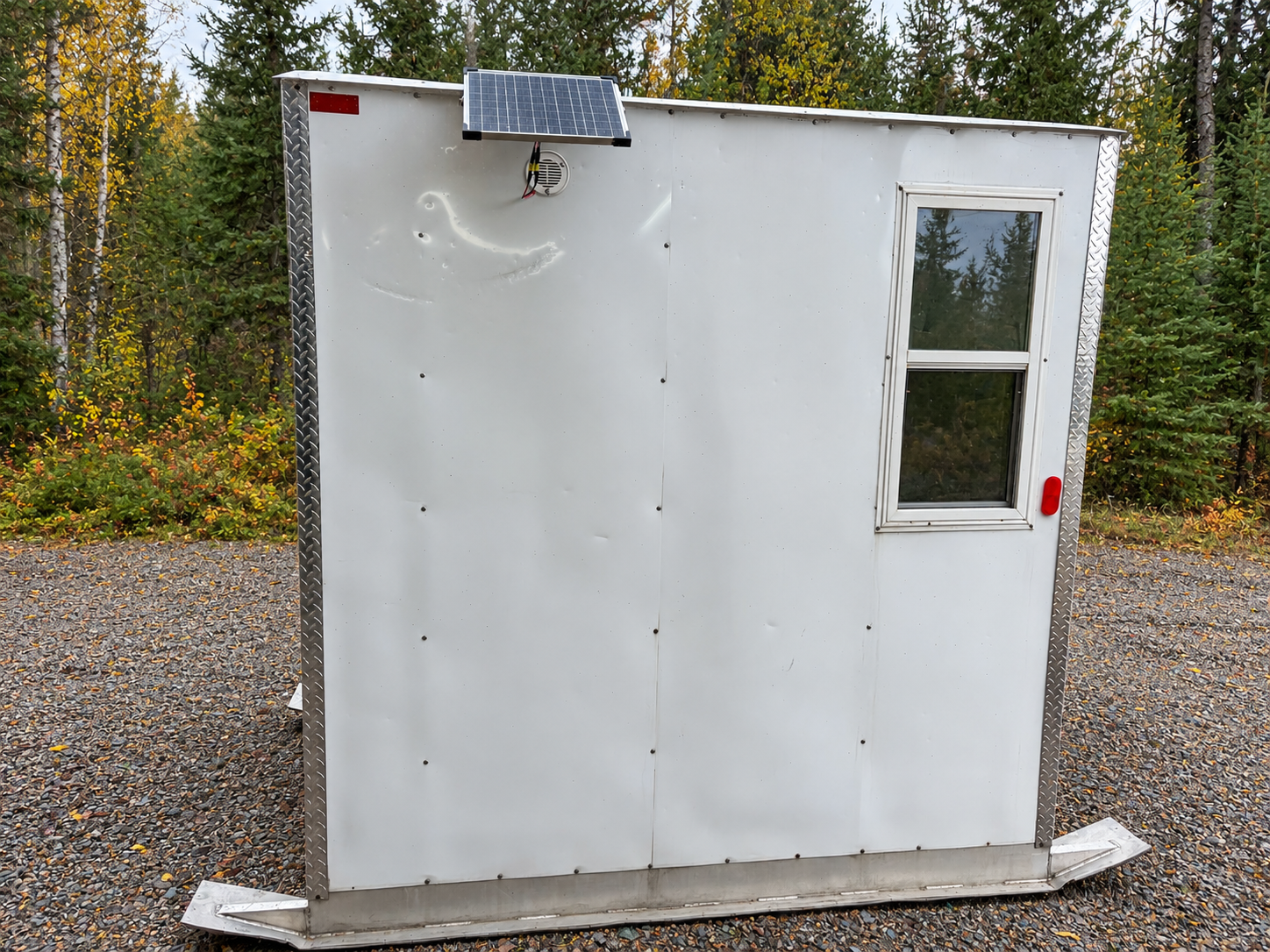 White skid fish house in evergreen woods.png