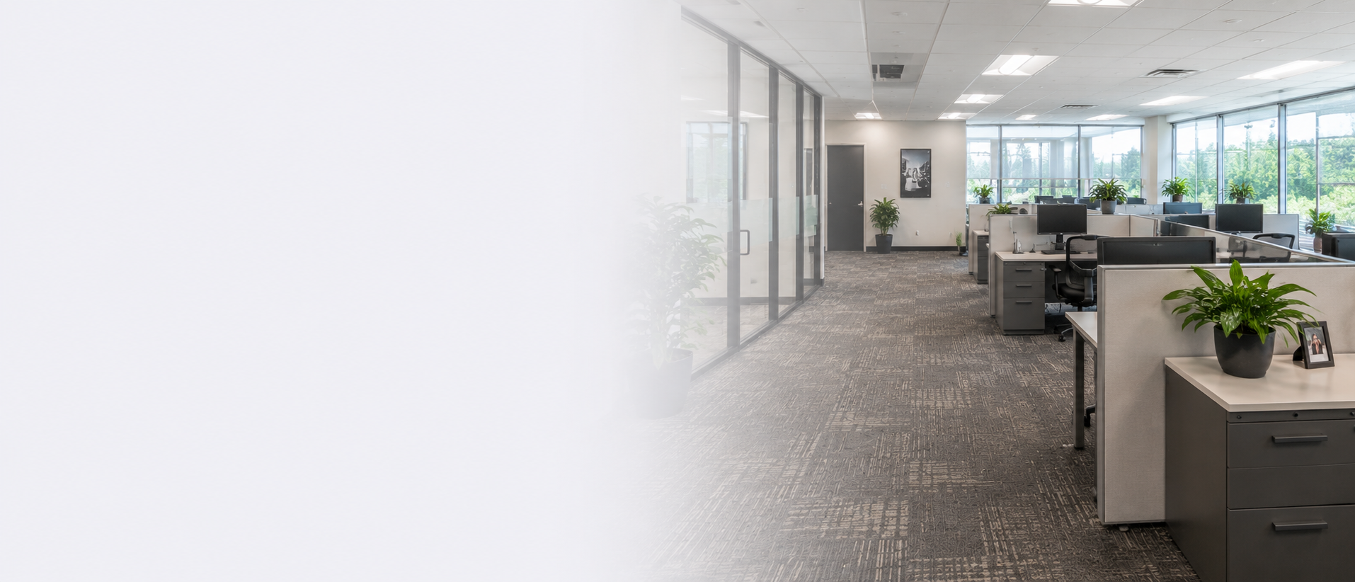 Clean professional office with workstations, computers, glass offices and large windows.