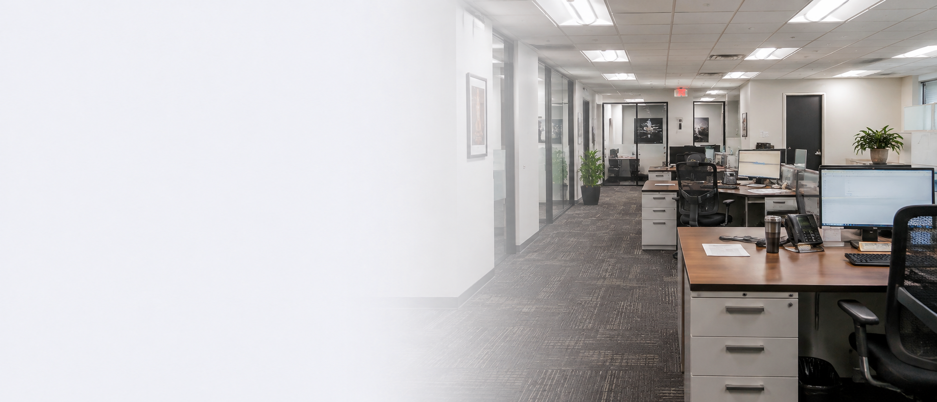 Clean professional office with workstations, computers, glass offices and large windows.