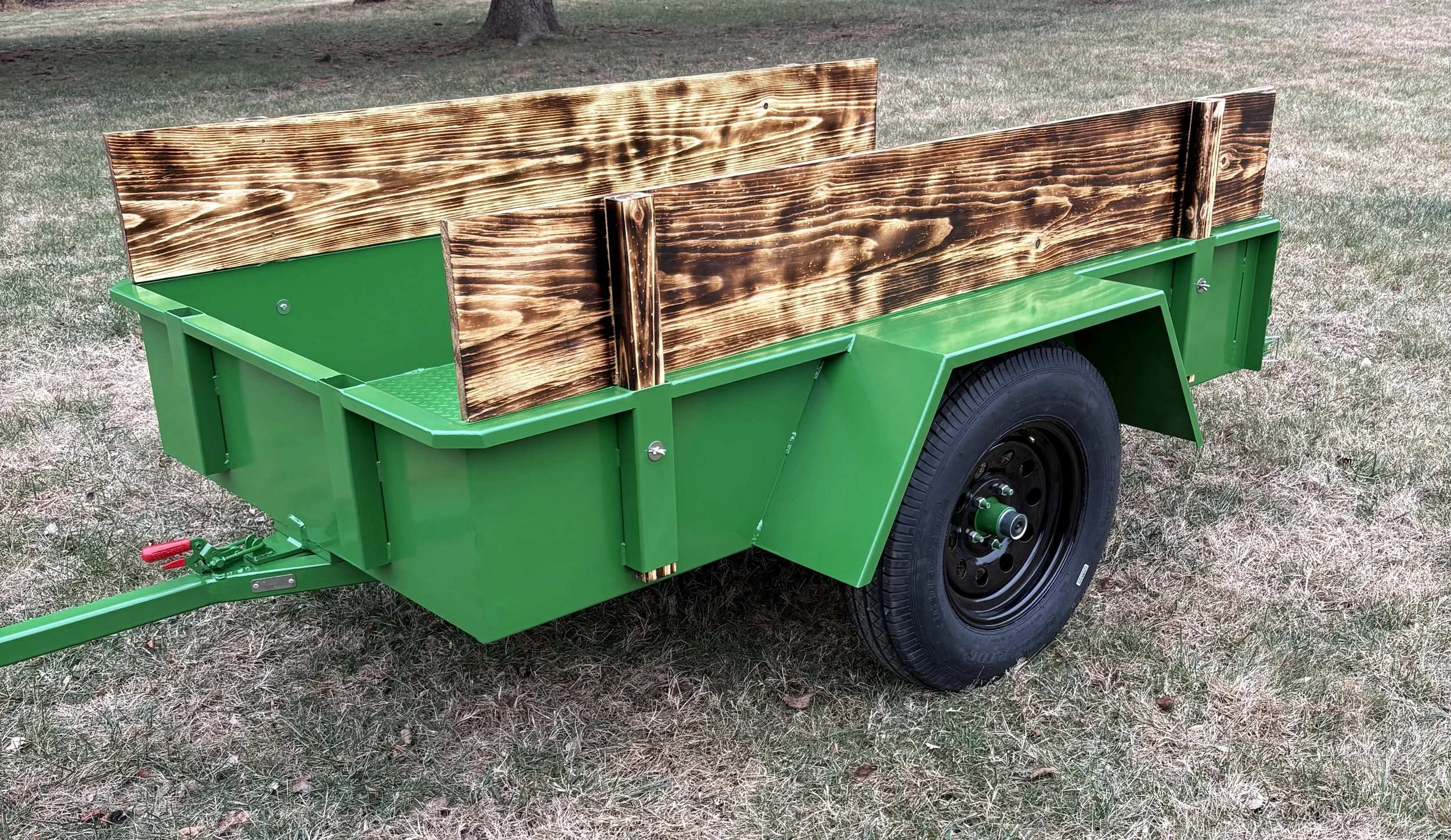 Green utility trailer with wooden sides parked on a grassy area in Chadds Ford PA