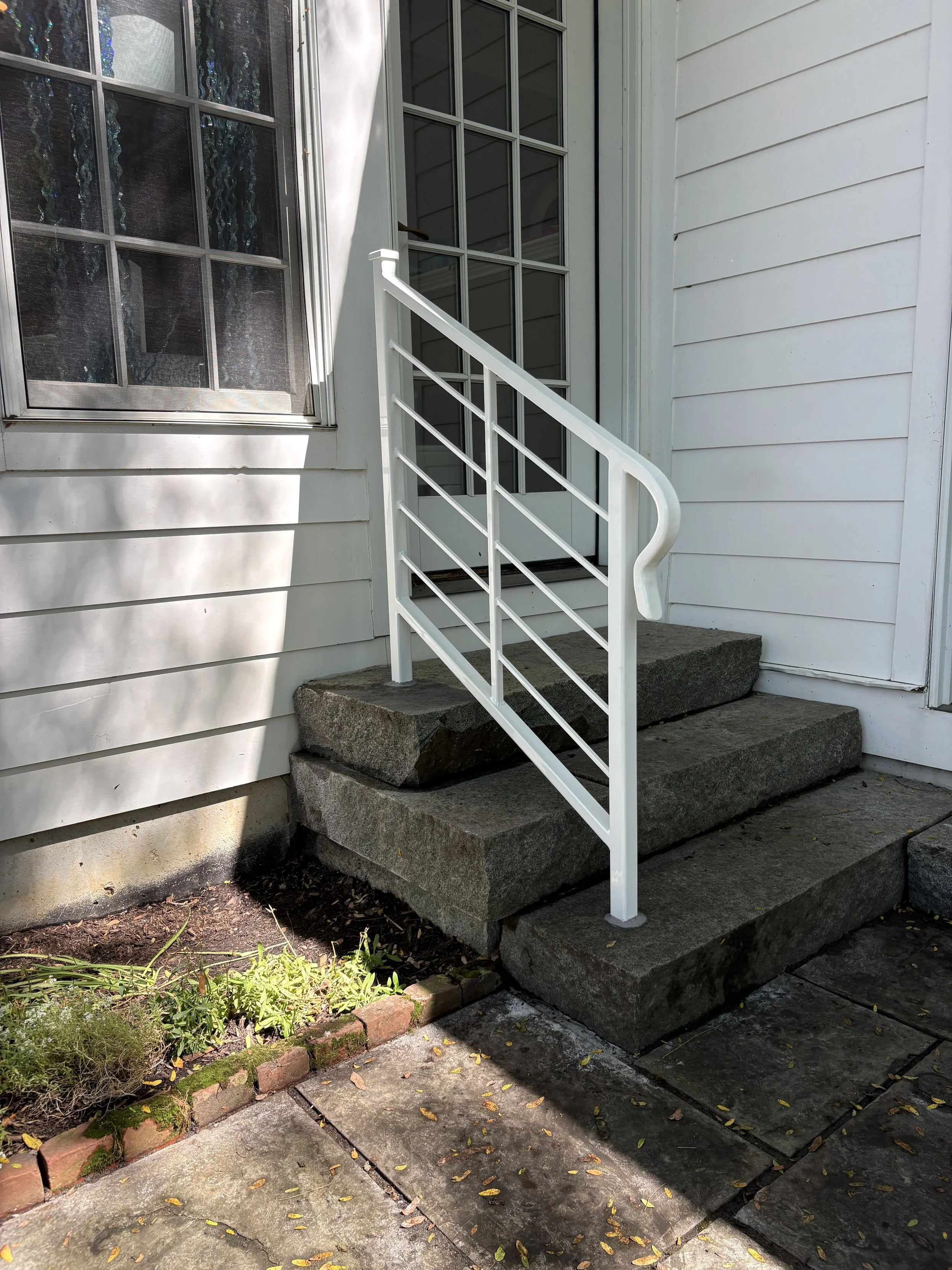 Custom white railings and steps leading up to a porch with a white exterior wall and windows. in Greenville DE