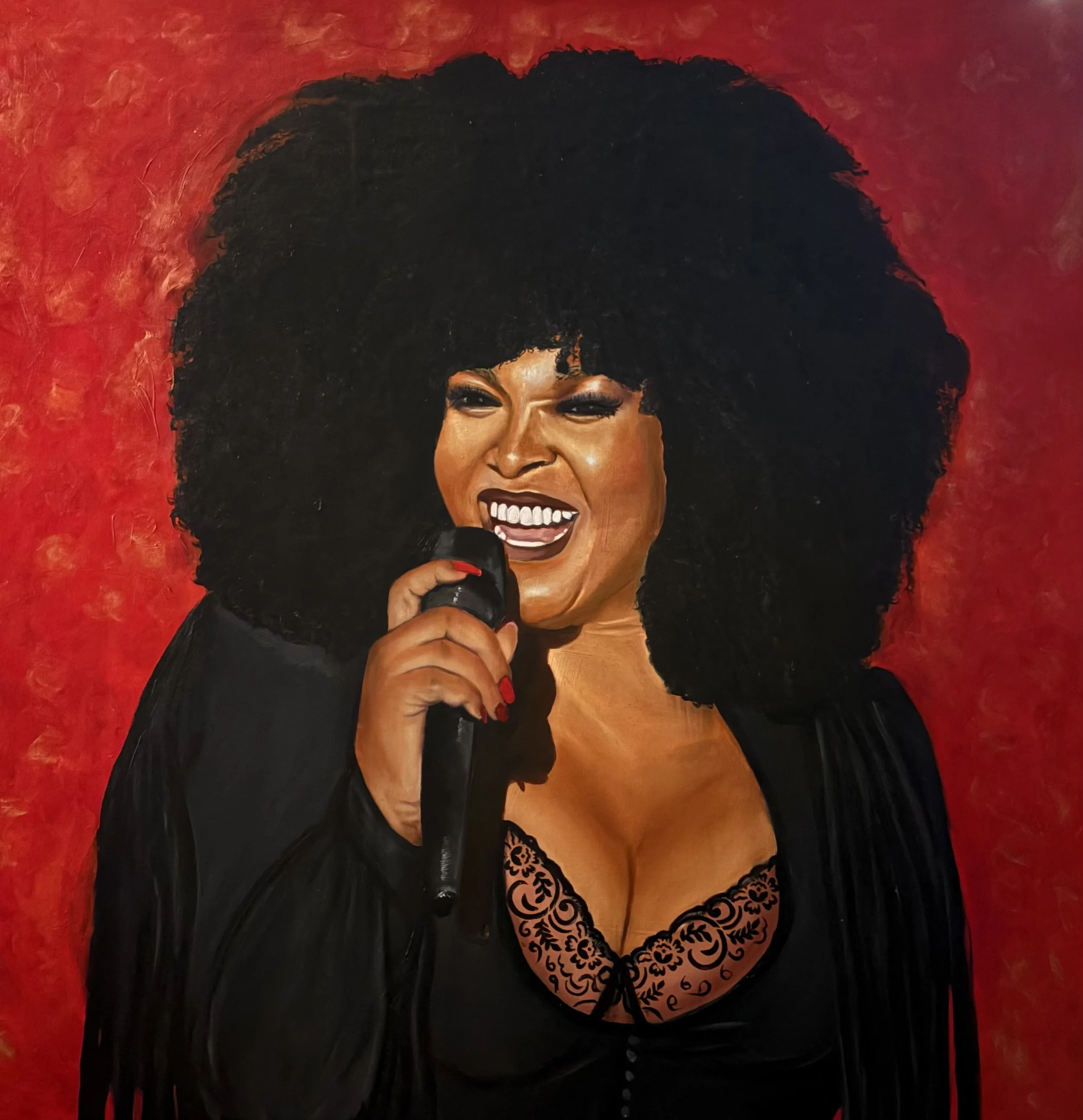 Painting of a woman with dark skin, black curly hair, holding a microphone, smiling, wearing a black lace top, set against a red background.