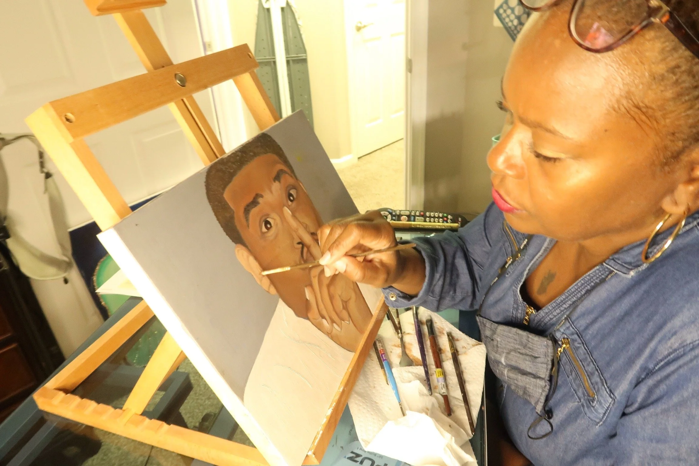 A woman painting a portrait of a young man with short hair on a canvas in an art studio.