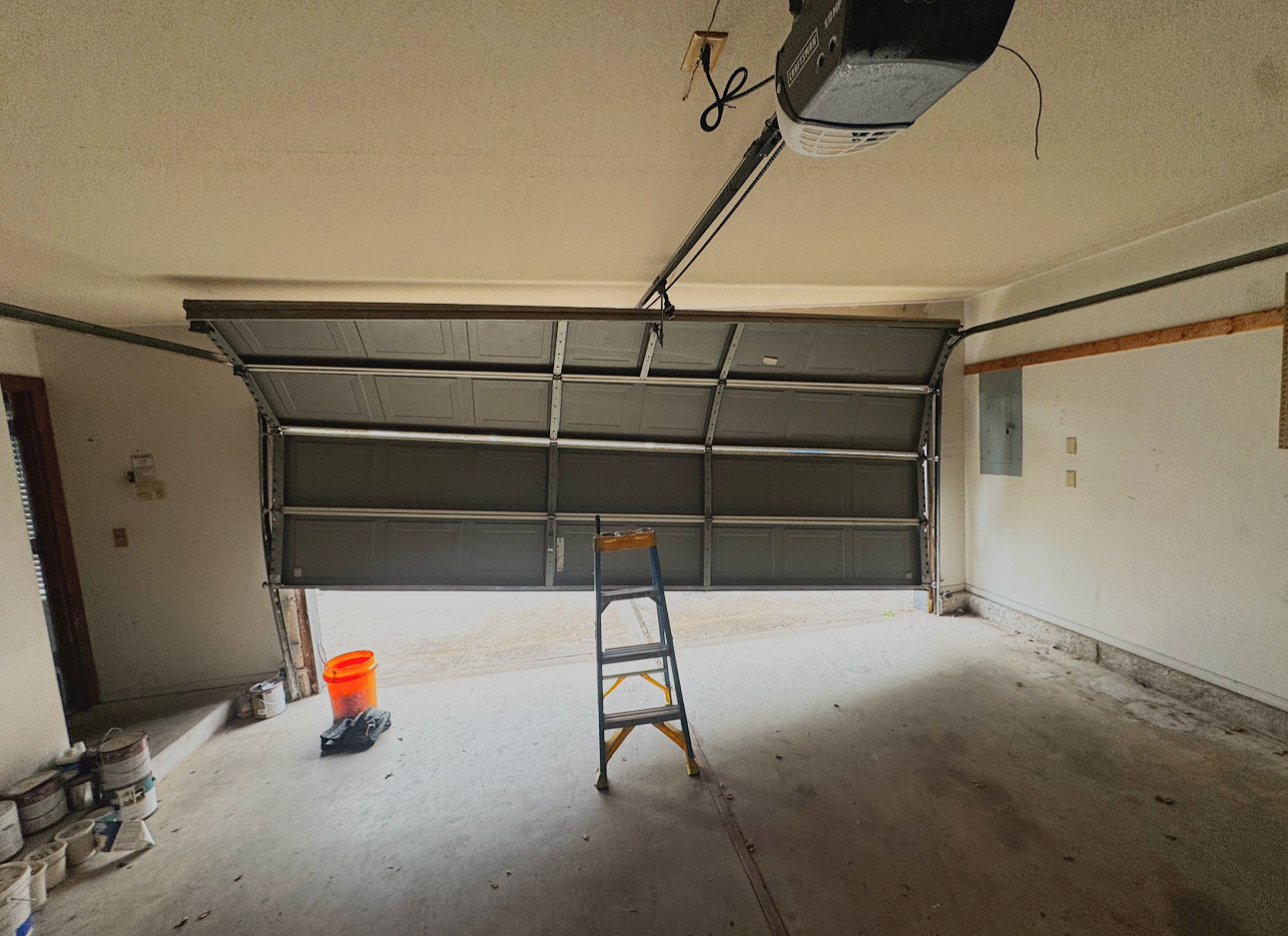 an interior look at a crooked garage door partially out of the track