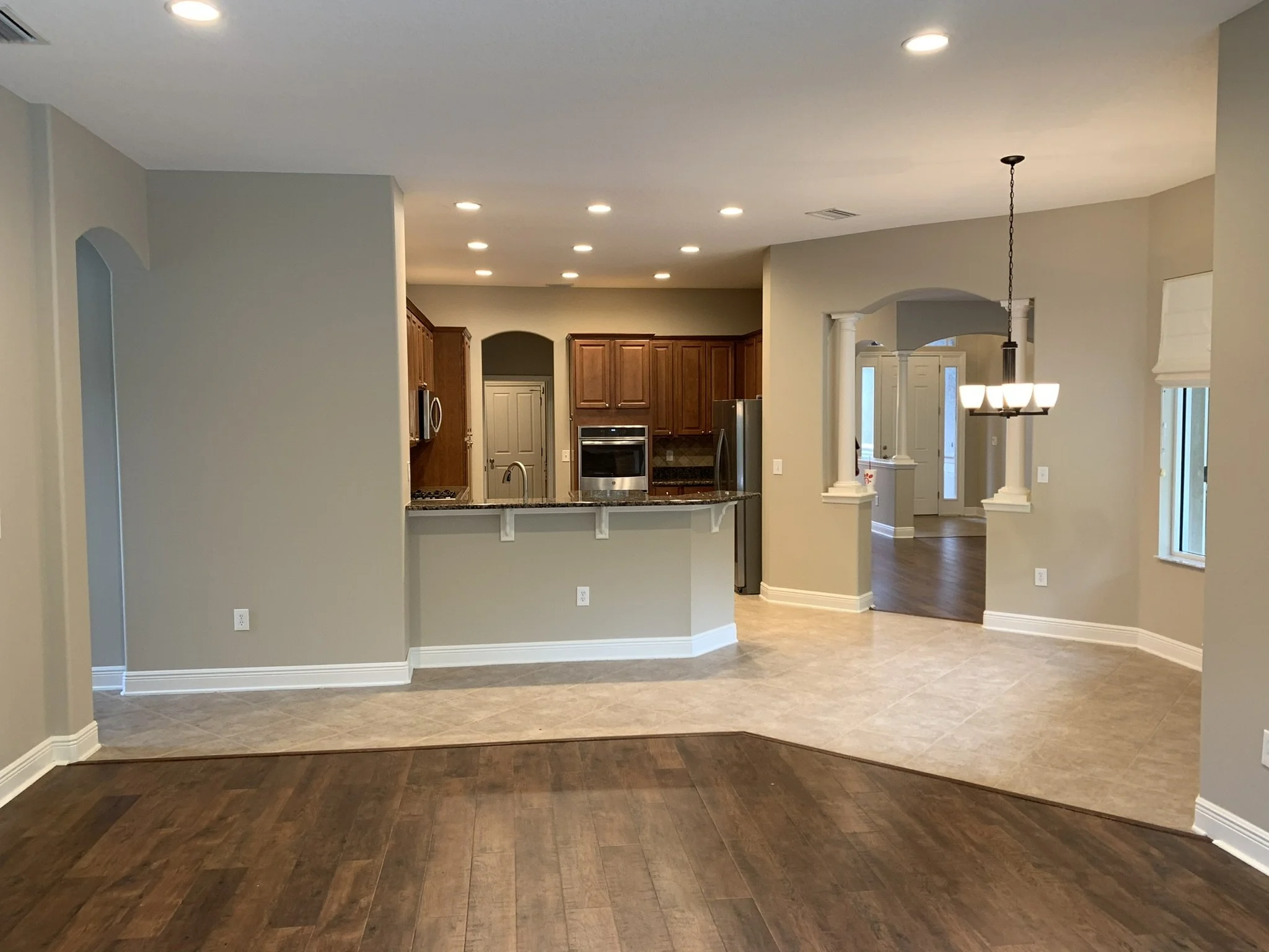 Professional interior painting of open-plan living room and klitchen with grey walls and white trim by HavenForged in Sarasota, FL.