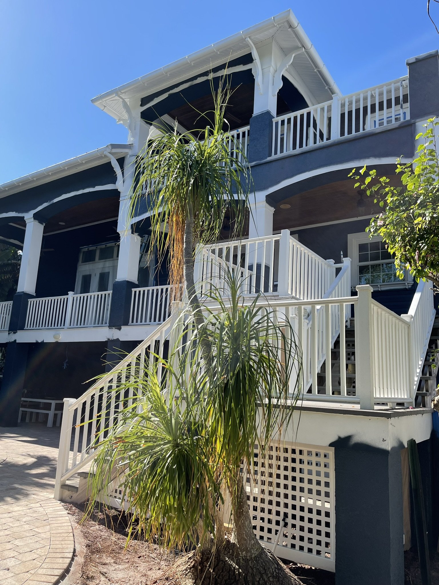 Exterior painting in progress with blue siding and white trim and railings being finished by HavenForged in Sarasota, Florida.