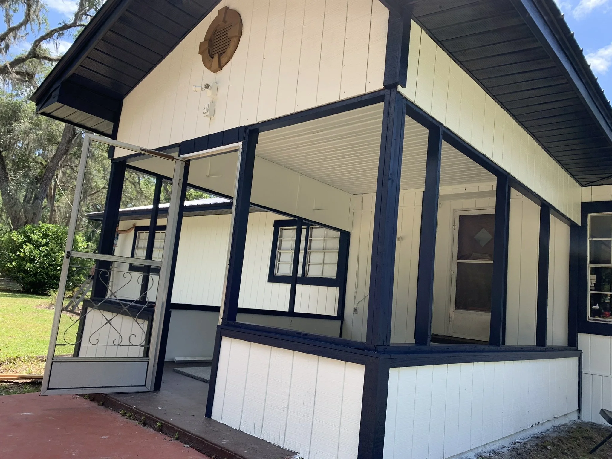 Freshly painted navy-blue and white home exterior and screened porch by HavenForged in Sarasota, Florida.