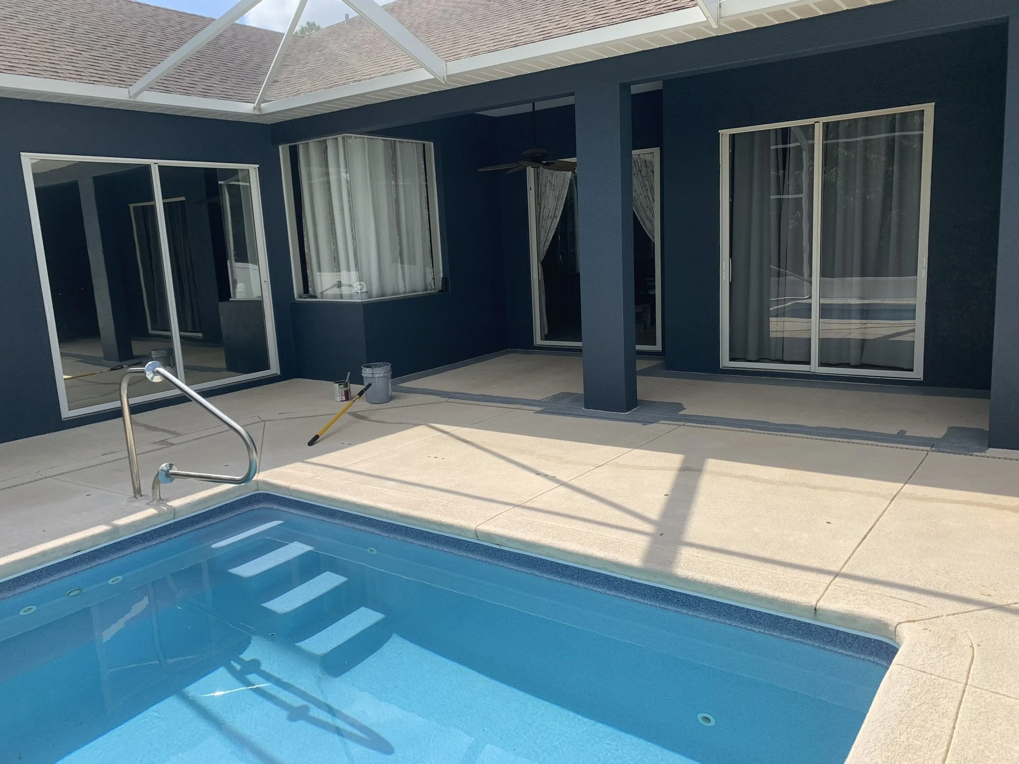 Property maintenance and exterior painting of covered pool patio with navy-blue walls and white trim by HavenForged in Sarasota, FL.