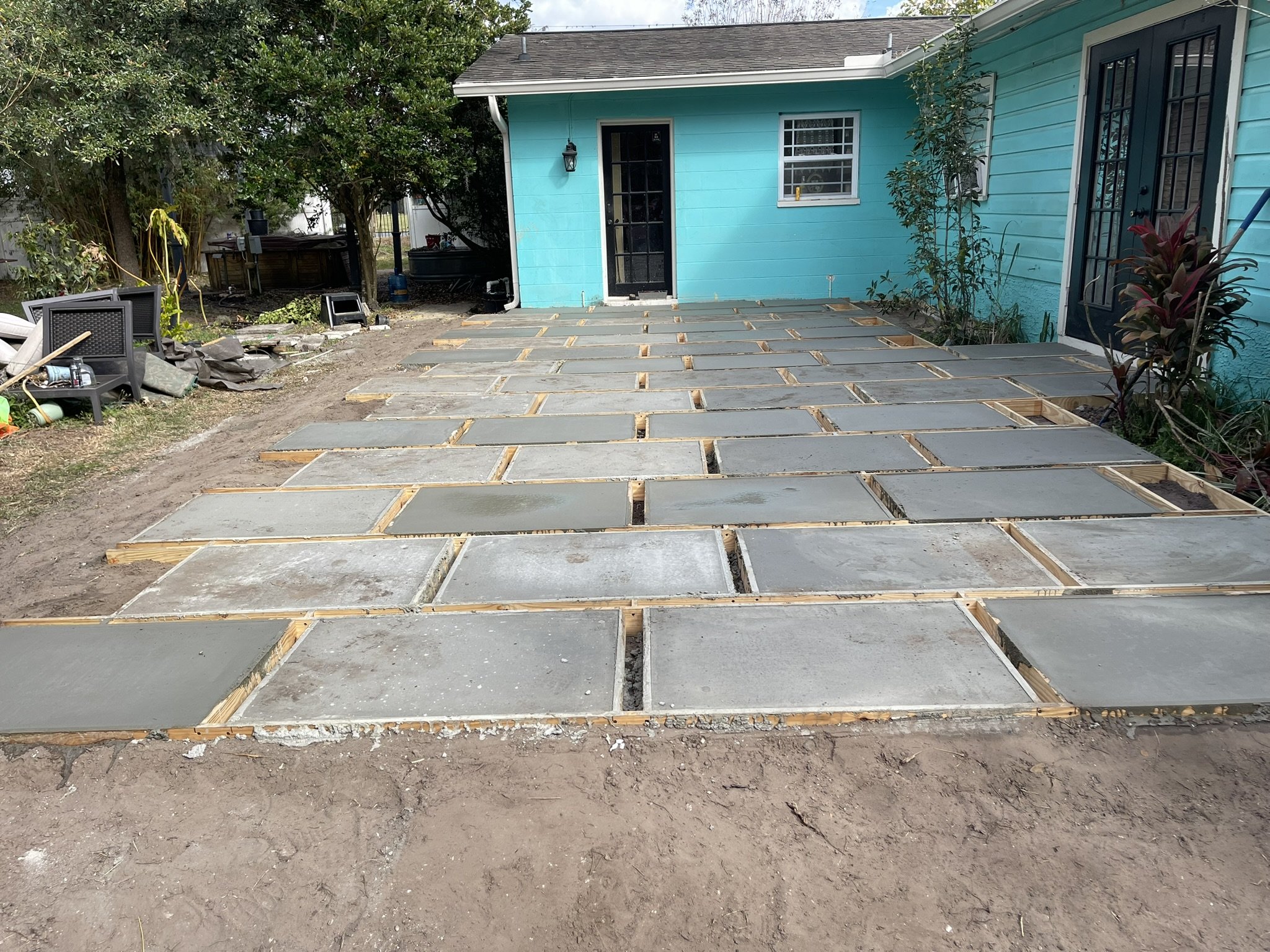 Custom concrete patio construction with individually formed slabs and 3-inch pebble stone joints by HavenForged in Sarasota, FL.