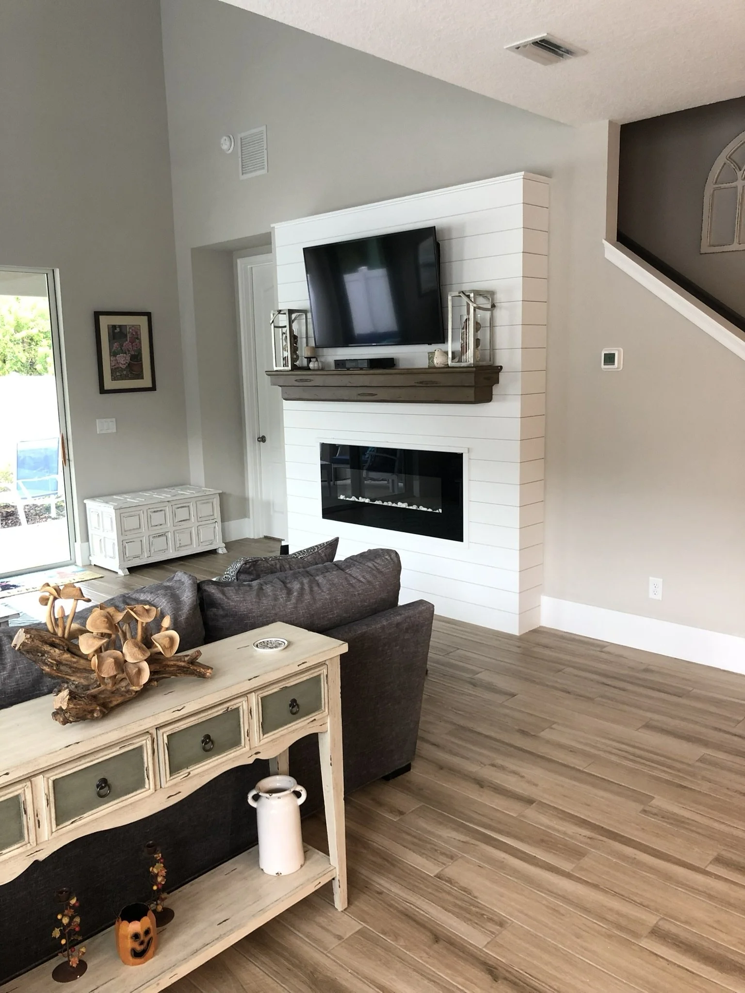 Completed interior painting update with freshly painted walls, white trim, wood flooring, and fireplace feature by HavenForged Group in Sarasota Florida.