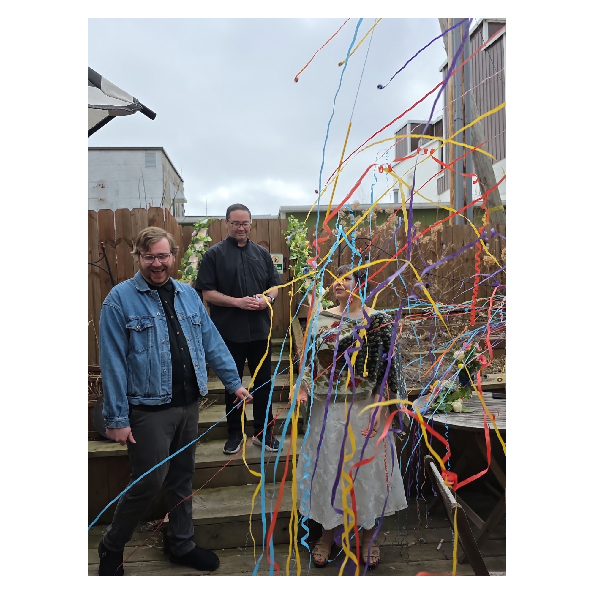 People celebrating at an outdoor party with colorful streamers and decorations.