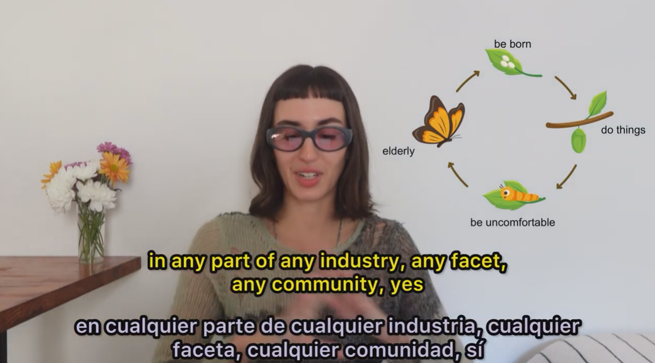 Woman standing in front of a whiteboard with a circular diagram featuring leaves, a butterfly, and caterpillar, illustrating a cycle of being born, doing things, feeling uncomfortable, and becoming elderly.