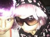 Two young women wearing pink wigs and sunglasses, taking a close-up selfie.