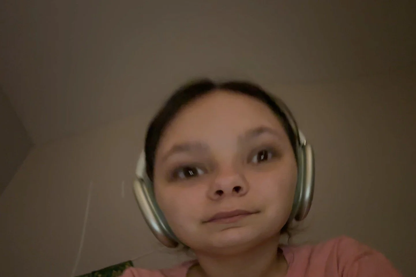 A woman wearing headphones taking a selfie, with a filter that distorts her face making her eyes and head appear larger.