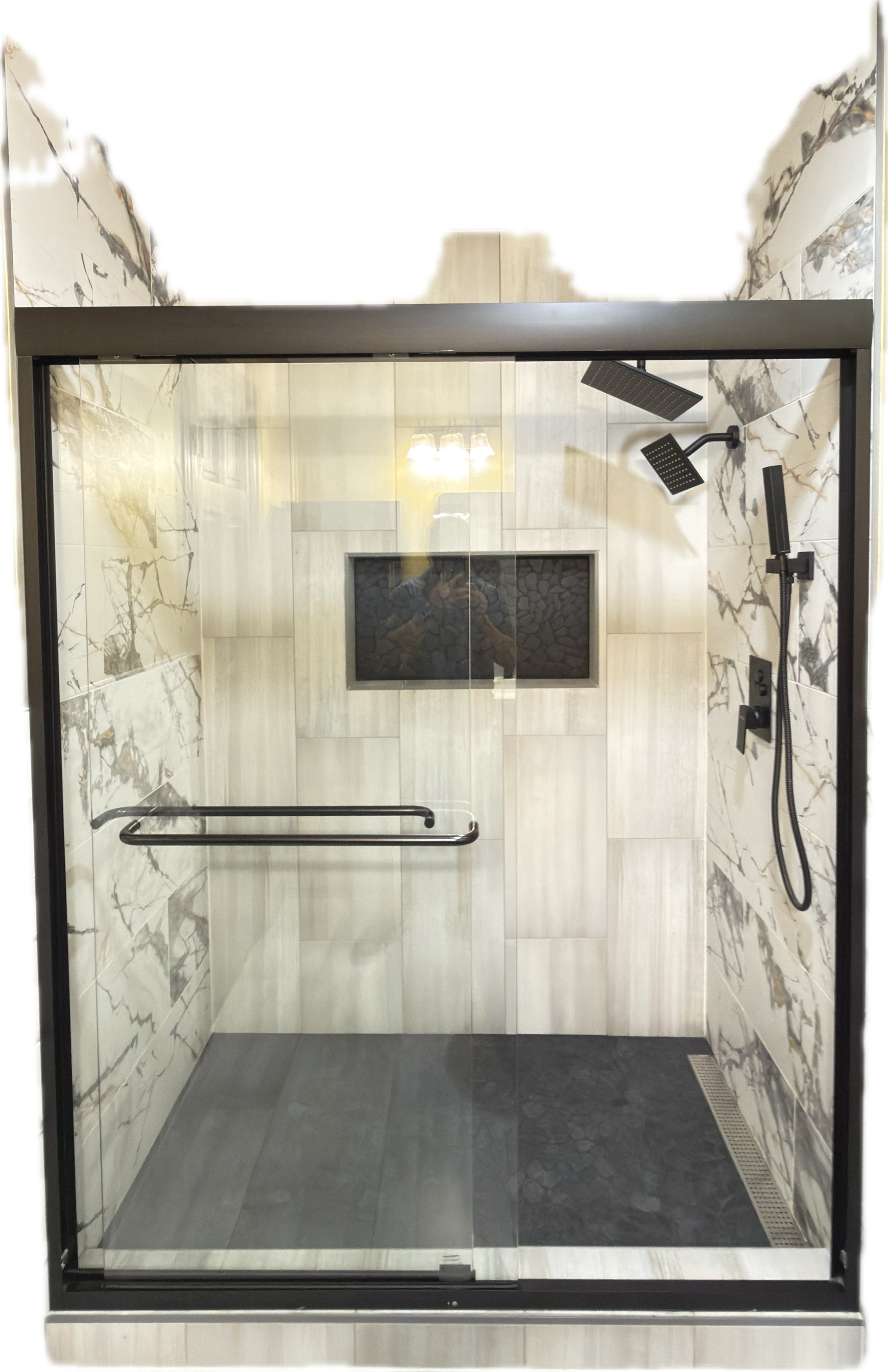 Modern walk-in shower with marble wall tiles, a rain showerhead, a handheld shower, a built-in niche with stones, and a glass door.