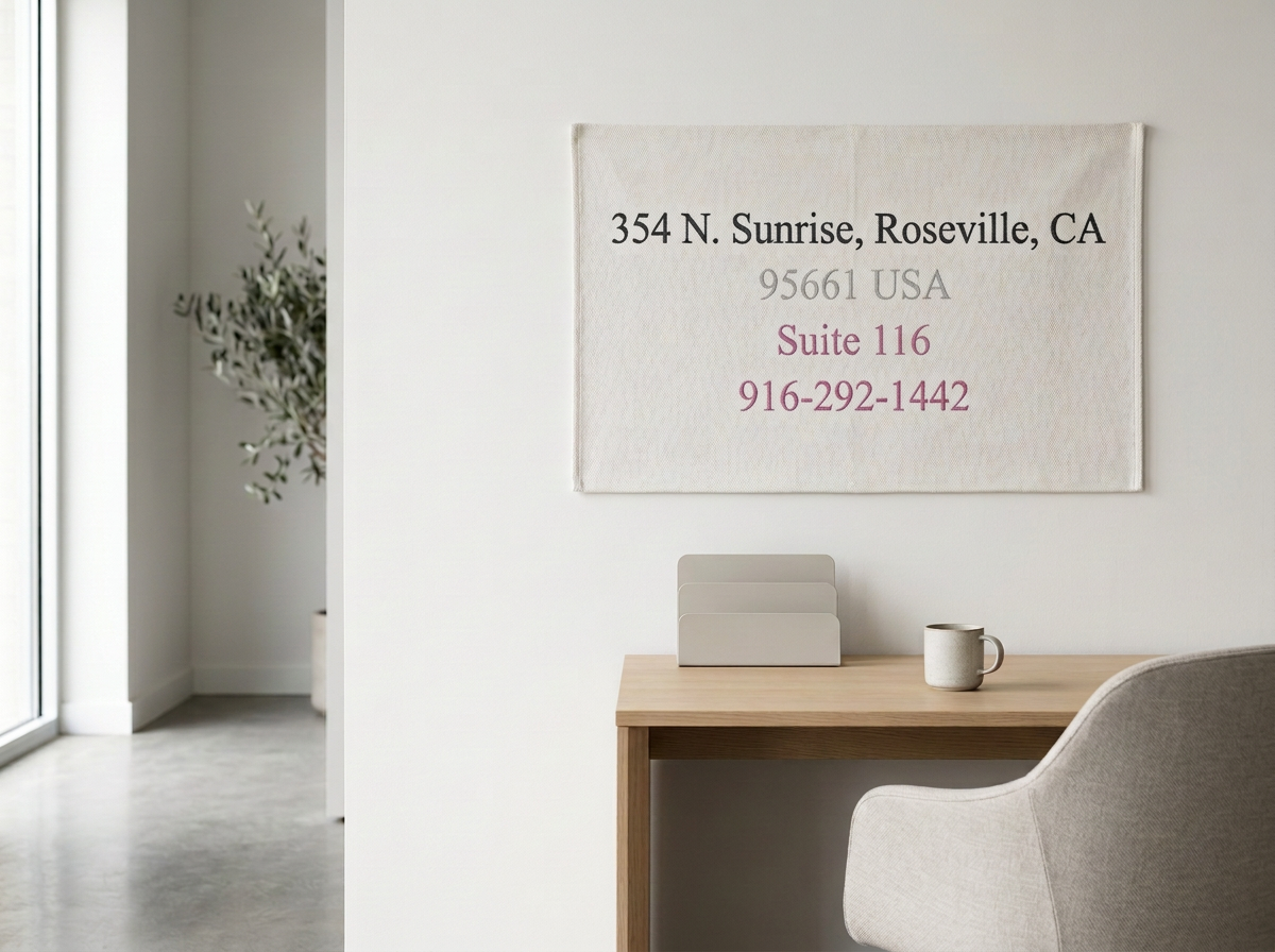 Interior of a modern office with a white wall, a beige desk, a gray chair, a mug, and a fabric wall hanging with address details for 354 N. Sunrise, Roseville, CA.