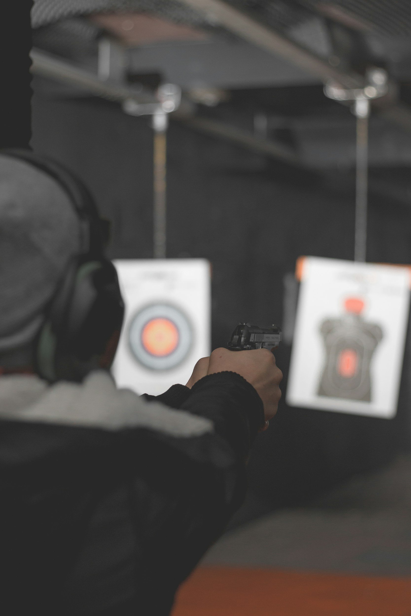 Person at an indoor shooting range aiming a handgun at a target with a digital target system.