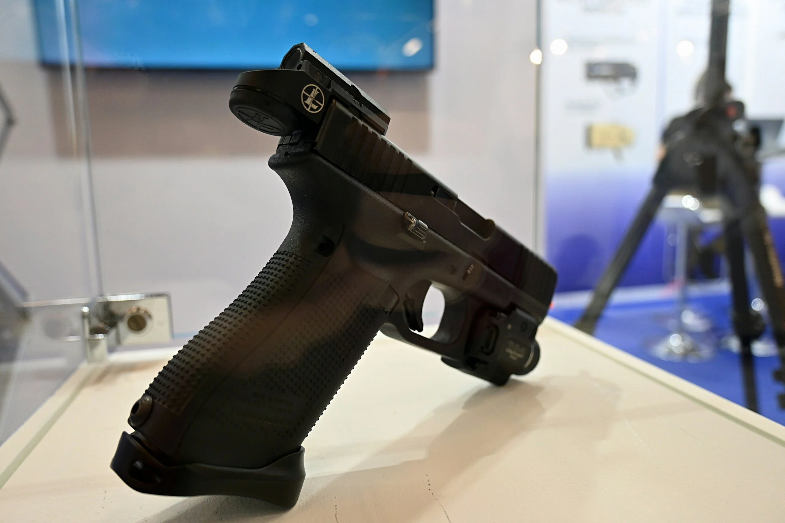 A black semi-automatic pistol on display in a glass case at an exhibition.