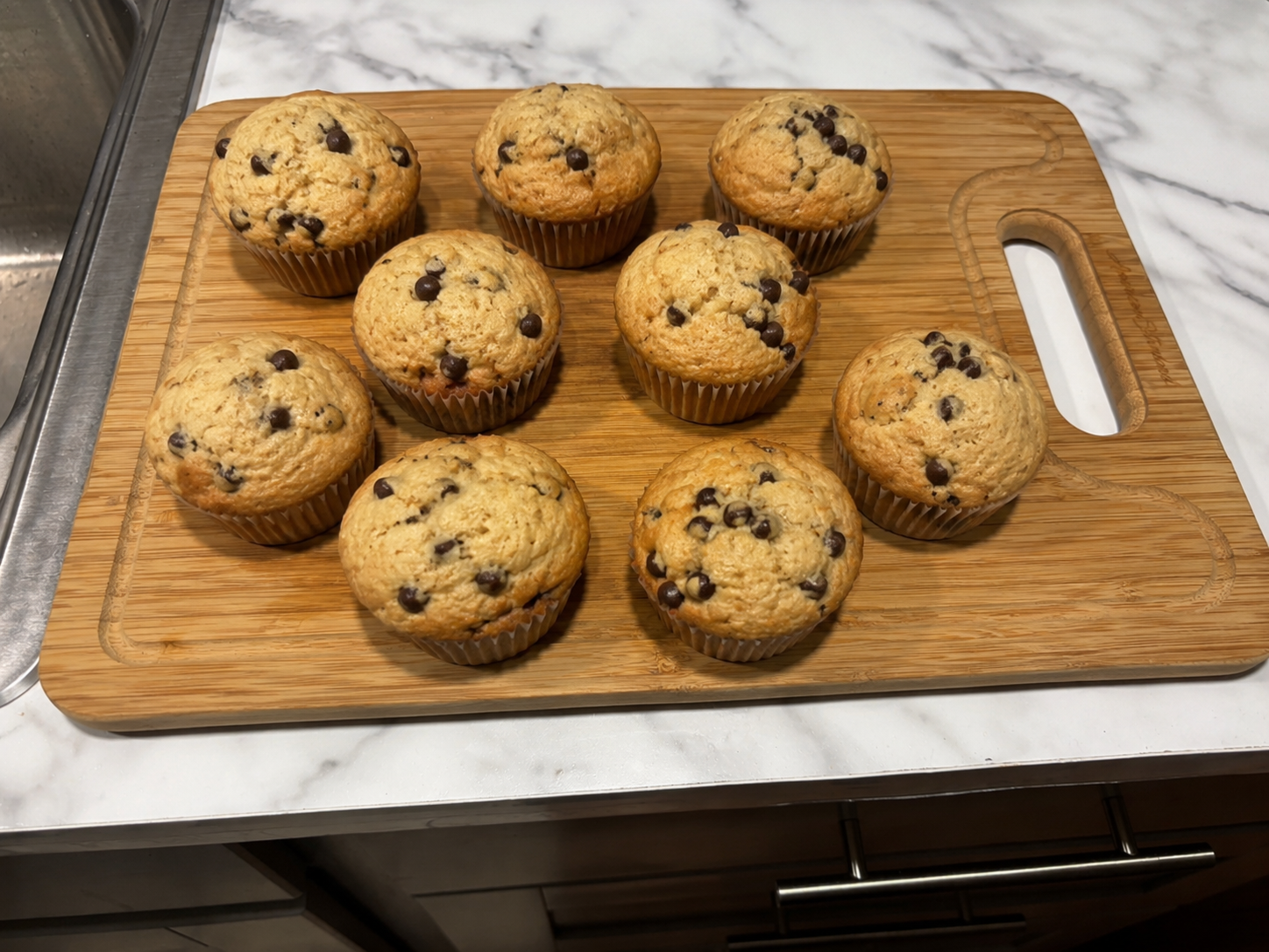 Fresh-milled flour chocolate chip muffins on a wooden cutting board.