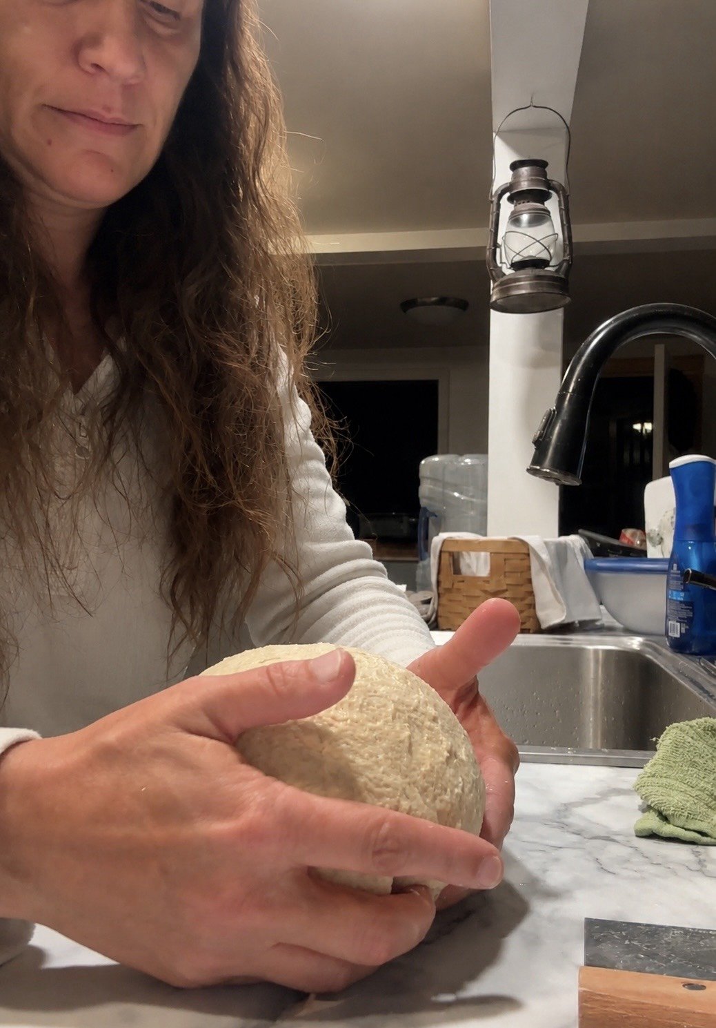 Pamela Wilday of Going Grains shaping fresh-milled flour dough on a marble countertop.