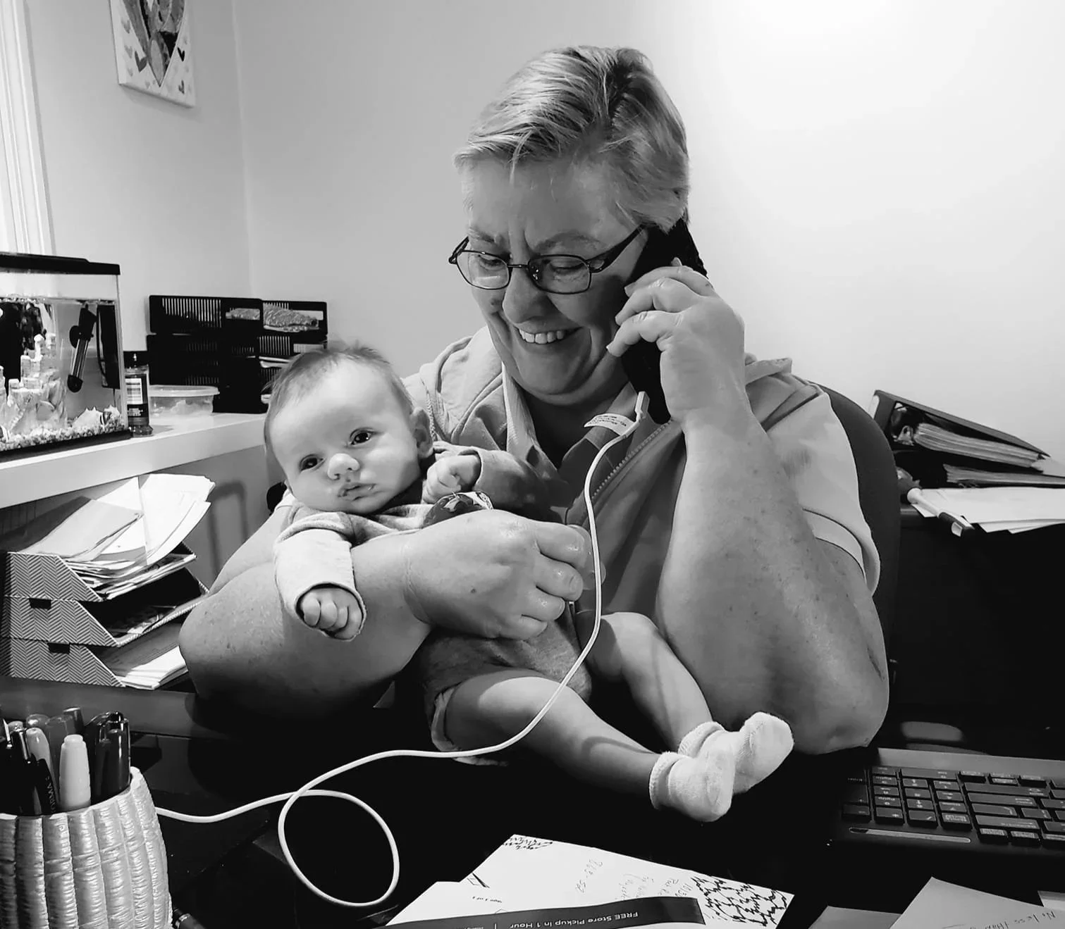 Smiling Breakthroughs LLC team member holding an infant while taking a phone call.