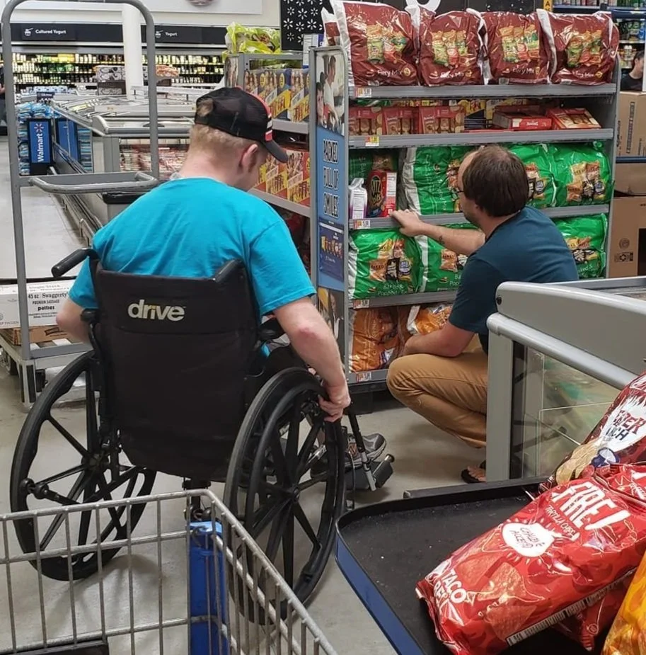 Breakthroughs LLC team member shopping in grocery store with client in a wheelchair.