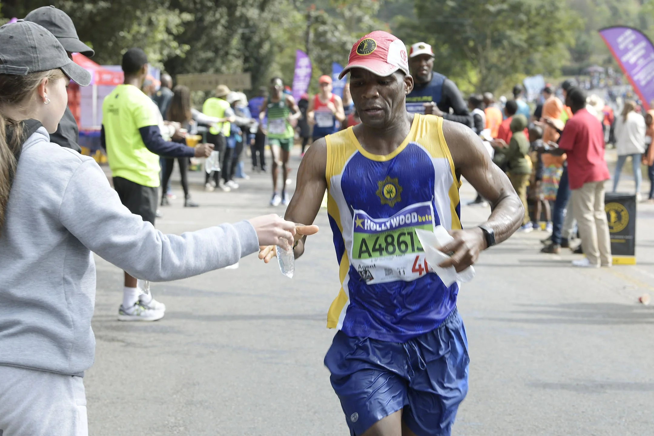 Female volunteer hands water to Comrades athlete during the annual ultimate human race