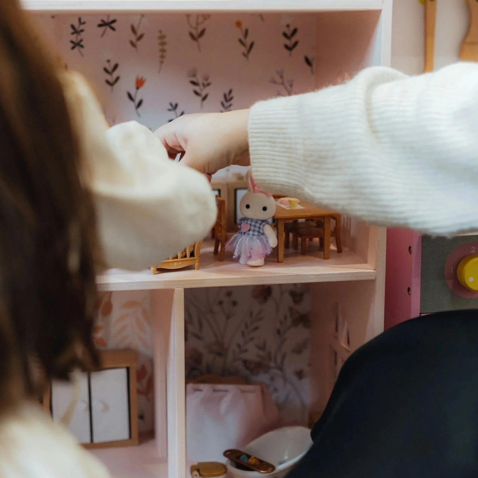 Close-up of a child and an adult playing with a dolls' house