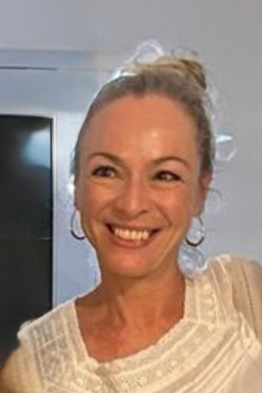 Play Therapist and consultant Zöe O'Reilly, Smiling woman with light-colored hair in a bun, wearing hoop earrings and a light-colored top