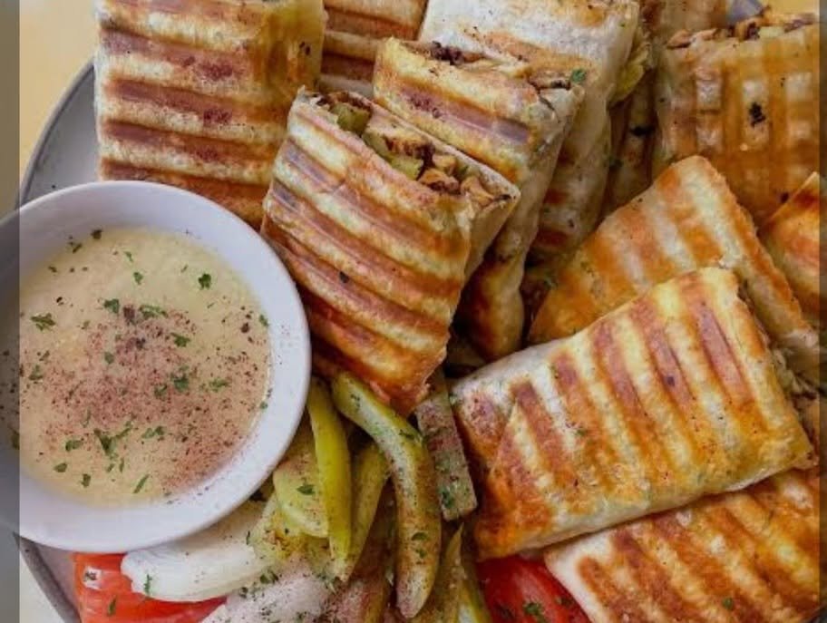 Grilled paneer tikka with a side of mint chutney and sliced vegetables.