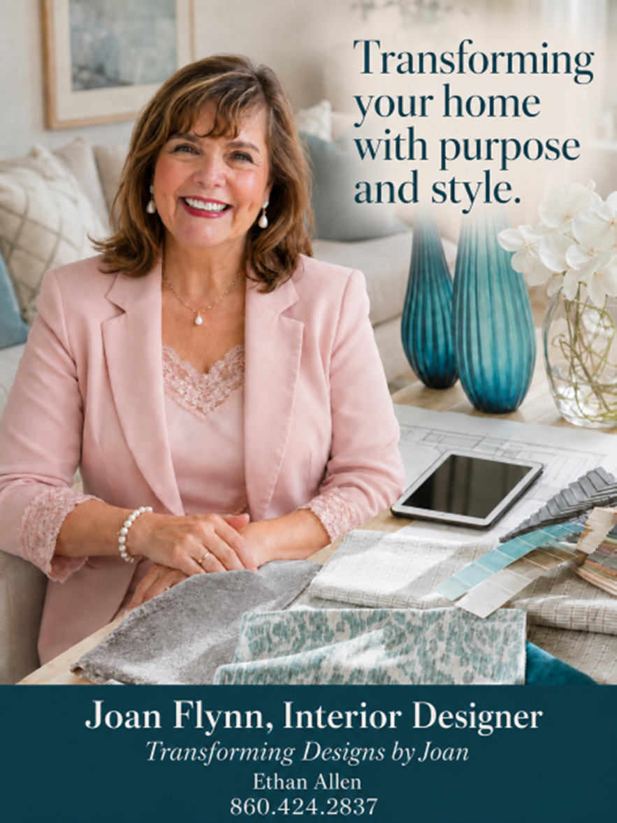 A professional woman with brown hair, wearing a pink blazer and matching lace top, sitting at a table with fabric samples, a tablet, and color swatches, smiling in a well-decorated interior space. The text overlays read 'Transforming your home with purpose and style.' and contact details for Joan Flynn, an interior designer.