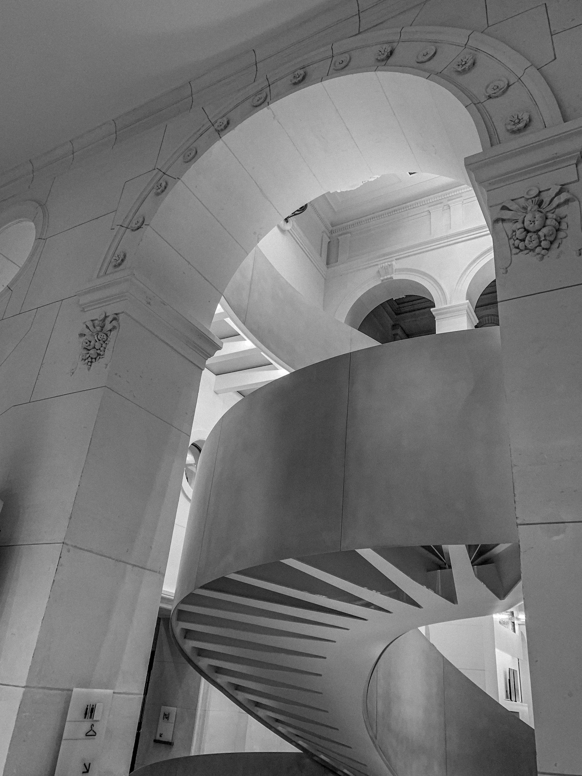 Black-and-white photograph of a curved architectural staircase.