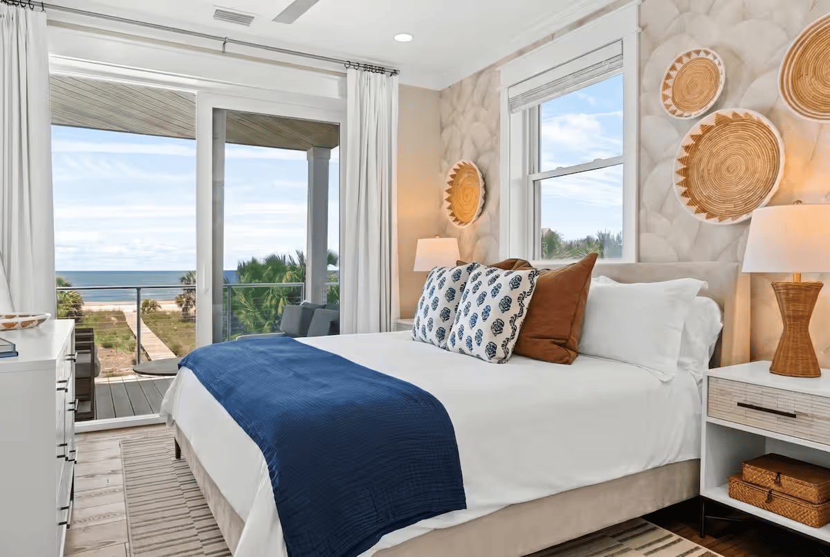 a king size bed in a coastal themed bedroom overlooking the ocean