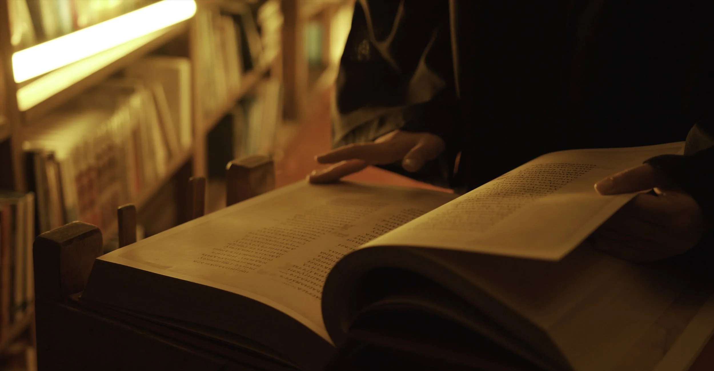 Hand resting on an open book in a library