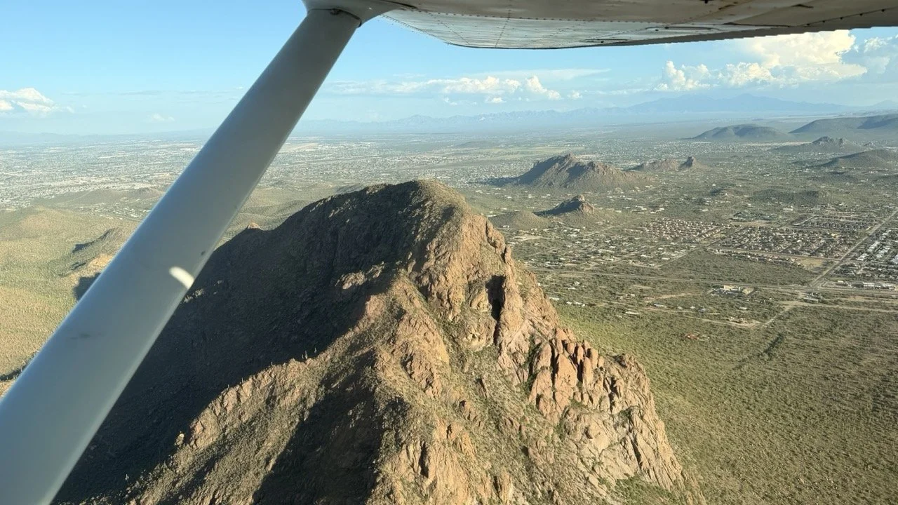 Desert peak and distant city from a Wind Walker Cessna in flight