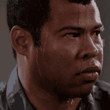 Close-up of a young man sweating profusely and a blank serious expression.