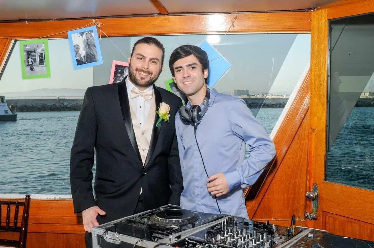 Wedding DJ Cliff Mertens with the groom at a yacht wedding, standing behind the DJ equipment.
