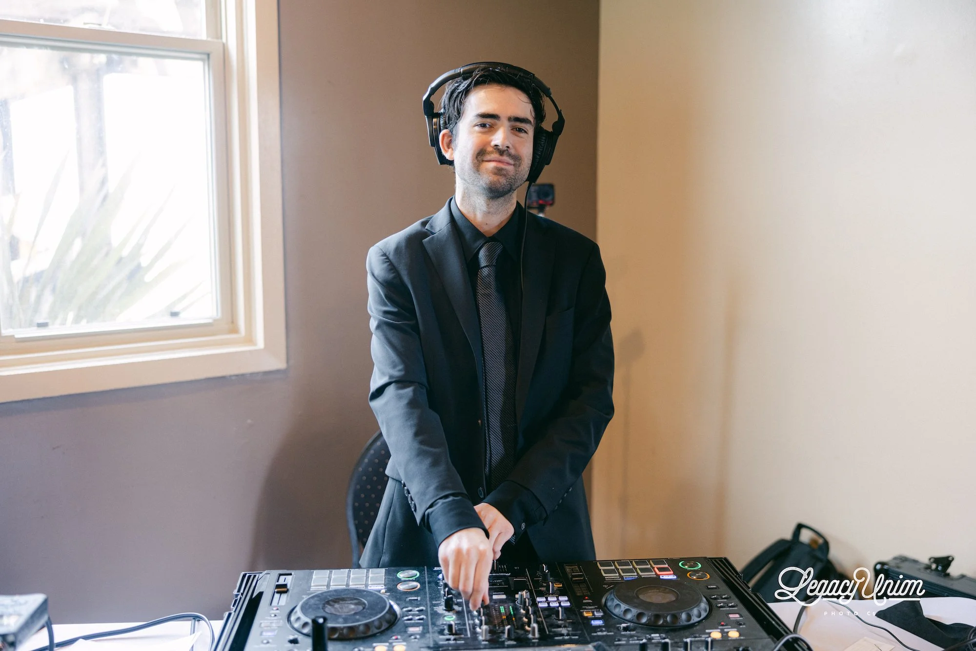 Wedding DJ Cliff Mertens in a suit, mixing with headphones on.