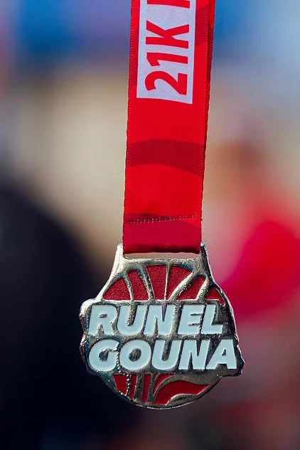 Finishers medal hanging from a red ribbon with "21K" printed on it, awarded for a race or marathon.