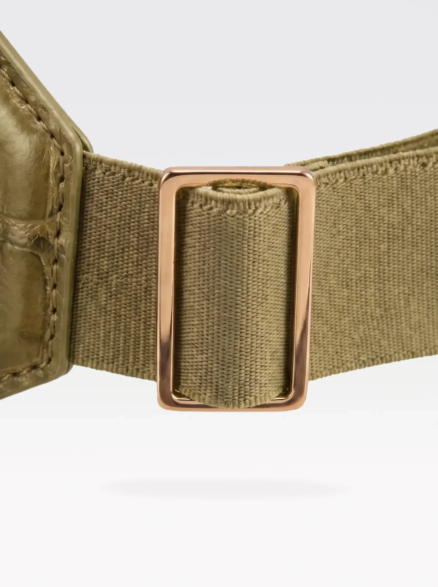 Close-up of the 24K gold-plated brass slider on the pistachio elastic band of a Sainte Sve Belt Croc