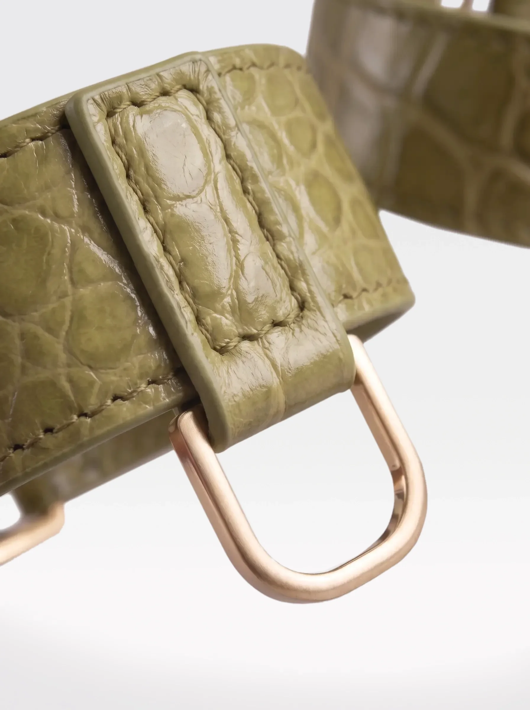 Close-up of the 24K gold-plated brass D ring on a pistachio crocodile-embossed lambskin wrist bracelet by Sainte Sve