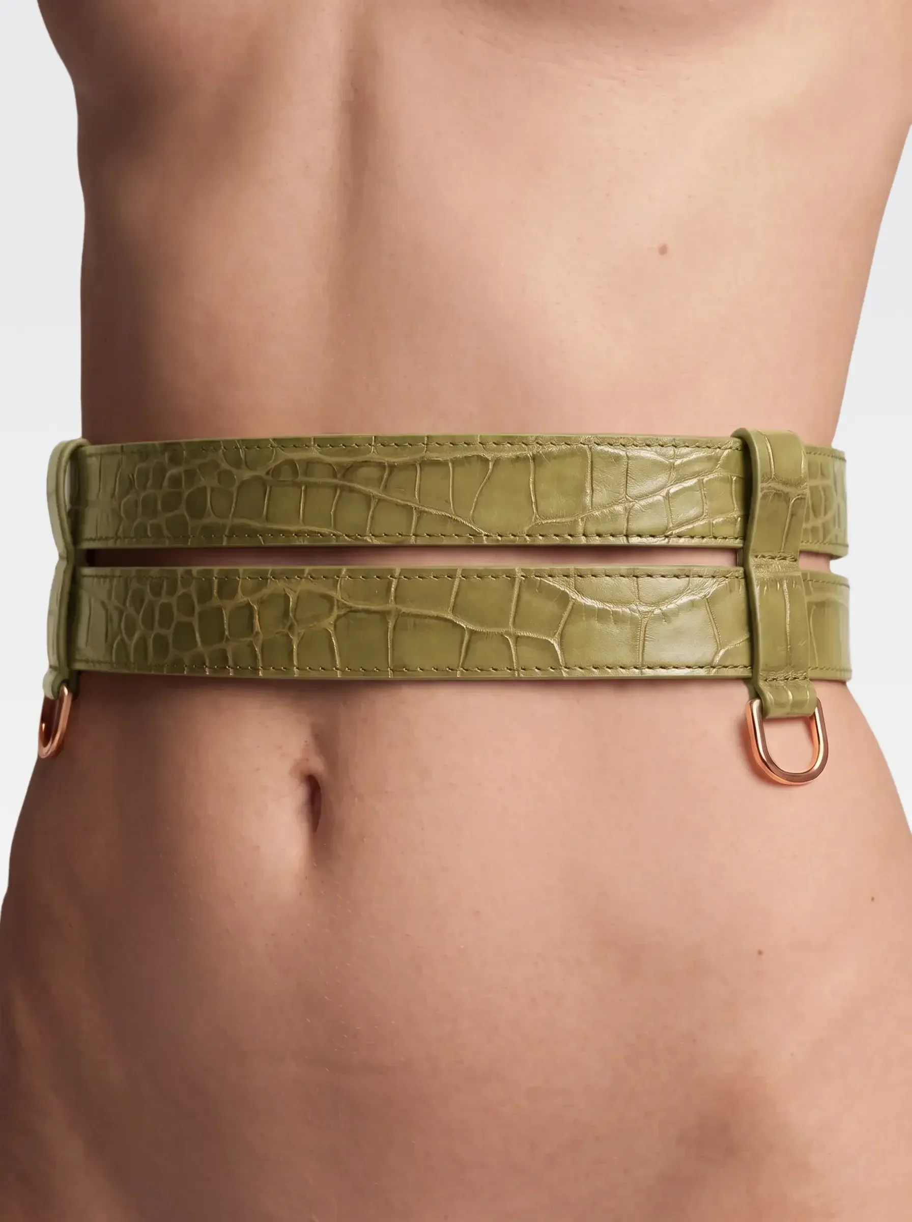 Sainte Sve Belt Croc in pistachio crocodile-embossed lambskin with 24K gold-plated brass D ring, worn at the waist, editorial image