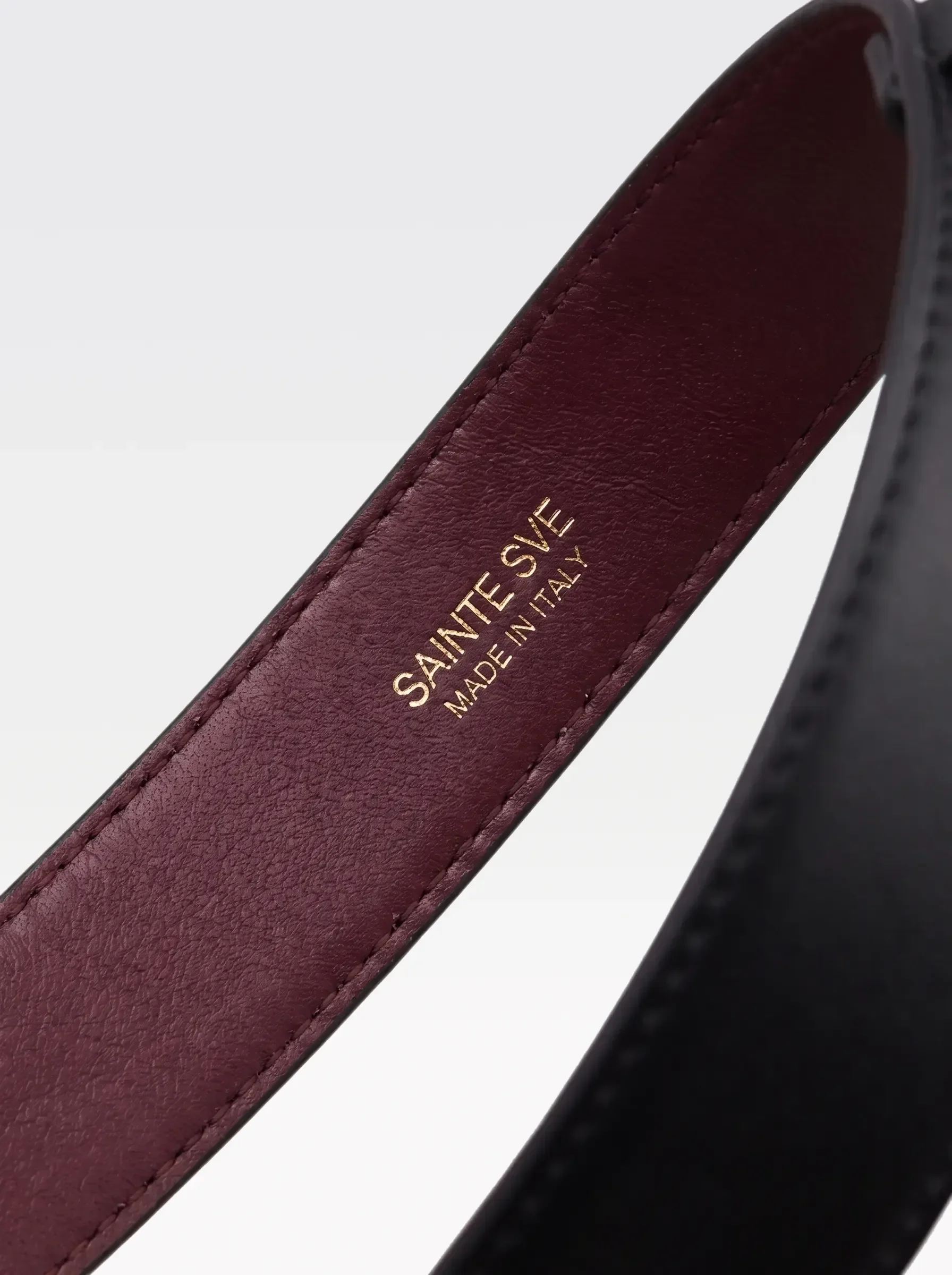 Close-up of the burgundy nappa lambskin lining of the Sainte Sve Garters Nappa with the foil-stamped Sainte Sve Made in Italy logo